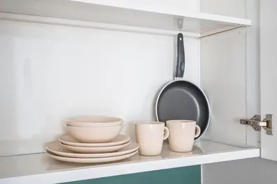 a kitchen shelf with cups and a pan on it at Spacious Studio With Dubailand Charm in Dubai