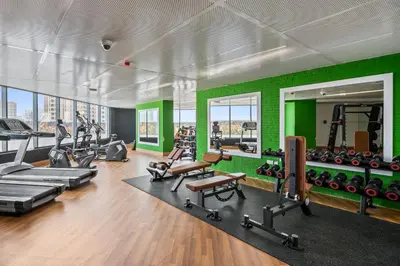 a gym with a green wall and tread machines at Bright Studio In Vibrant Dubailand District in Dubai