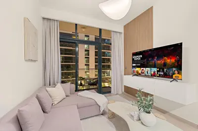 a living room with a couch and a flat screen tv at Cozy 1BR with Pool View & Balcony in Dubai