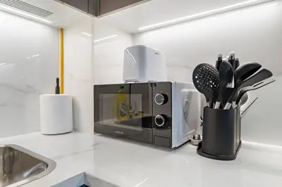a kitchen counter with a microwave and some utensils at Cozy 1BR with Pool View & Balcony in Dubai