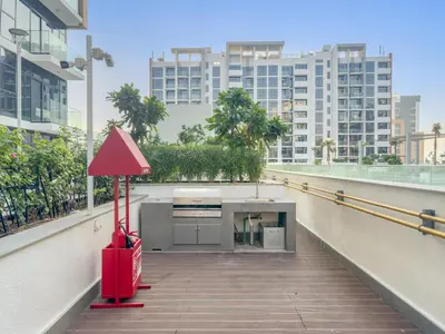 a red object on a balcony with buildings at Cozy 1BR with Pool View & Balcony in Dubai