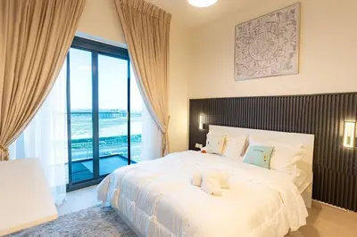 a bedroom with a large white bed with a large window at Cozy studio in Azizi Riviera with beautiful views in Dubai