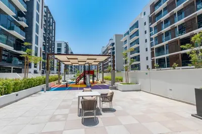 a patio with a table and chairs and a playground at Cozy studio in Azizi Riviera with beautiful views in Dubai