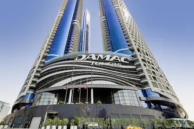 a building with a sign on it with two tall buildings at Stylish 1BR in Damac Towers by Paramount B, Business Bay by Deluxe Holiday Homes in Dubai
