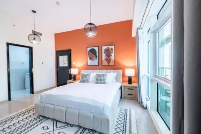a bedroom with an orange accent wall and a bed at Stylish 1BR Apartment! Near Metro & Stroll to Dubai Marina in Dubai