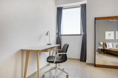 a desk and chair in a room with a bedroom at Blueground Sadaf sea view elevator gym DXB-925 in Dubai
