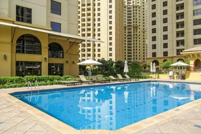 a large pool with chairs and umbrellas and buildings at Blueground Sadaf sea view elevator gym DXB-925 in Dubai