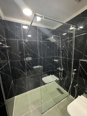 a black tiled bathroom with a shower and a toilet at Jvc diamond 1 home in Dubai