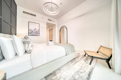 a white bedroom with a bed and a chair at Chic 2BR with Iconic Dubai Eye and Palm Views in Dubai
