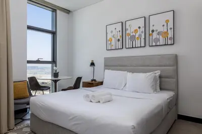 a bedroom with a large white bed and a table at Waves - Stylish 13th-Floor Studio with Top-Notch Amenities in Dubai