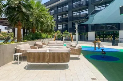 a patio with wicker furniture and a swimming pool at Belgravia 3 - Bright One Bed with Garden View in Dubai