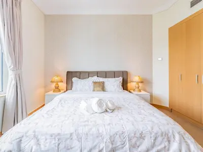 a bedroom with a large white bed with two lamps at Chic 4BR Apt Pool Palm Beach Club Dubai in Dubai
