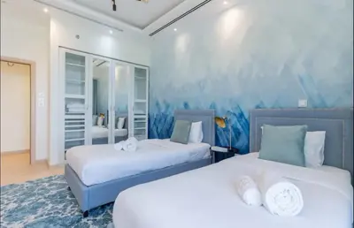 a bedroom with two beds and a blue wall at AWS Holiday Homes - Spectacular Sea Views in Dubai