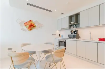 a white kitchen with a white table and chairs at AWS Holiday Homes - Memories by the Beach in Dubai