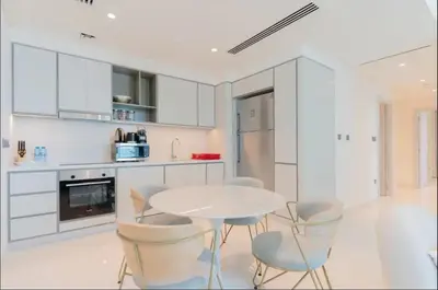 a white kitchen with a white table and chairs at AWS Holiday Homes - Memories by the Beach in Dubai