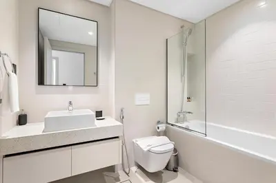 a bathroom with a sink and a toilet and a mirror at Silkhaus 1BDR with Beach Access in Marina Vista in Dubai
