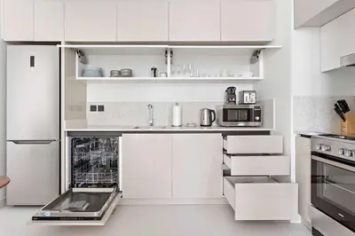 a white kitchen with white cabinets and appliances at Silkhaus 1BDR with Beach Access in Marina Vista in Dubai