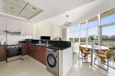 a kitchen with a sink and a table with chairs at Silkhaus Modern Studio in Reef Residence at JVC in Dubai
