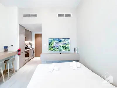 a white bedroom with a bed and a desk at Cozy Studio with Balcony & Stunning Views in Dubai
