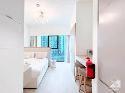 a white room with a bed and a desk at Cozy Studio with Balcony & Stunning Views in Dubai