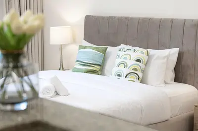 a white bed with pillows and a vase of flowers at JuliusHomes - Studio in Bay Square, Business Bay Dubai in Dubai