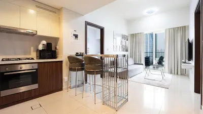 a kitchen with bar stools and a living room at Luxury 2BR apartment with Burj View GYM & Pool in Dubai