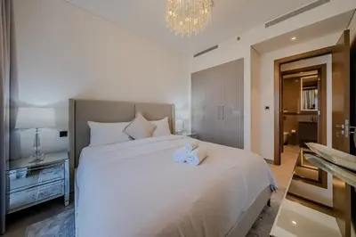 a bedroom with a large white bed and a chandelier at Stylish 1 BDR apartment in Sobha Waves in Dubai
