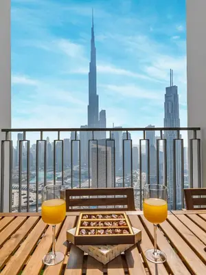 a table with two glasses and a tray of food on a balcony at Chic 4 Bedroom Apartment I Burj Khalifa & Fountain Views I Direct Access to Dubai Mall I Free Gym, Pool, Parking Wi-Fi and PS5 I by Skyline Serenity in Dubai