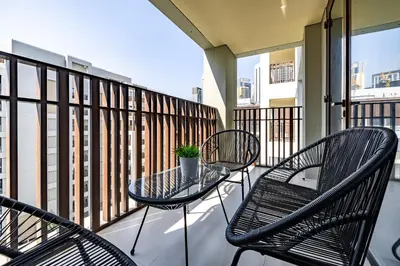 a balcony with three chairs and a glass table at Exquisite 1BDR apartment in Creek with Pool View in Dubai