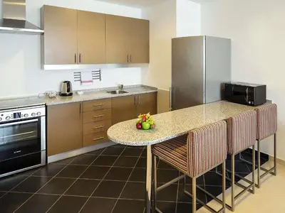 a kitchen with a table with chairs and a counter top at Adagio Premium Dubai Al Barsha in Dubai