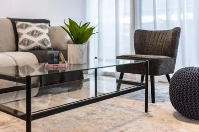 a glass coffee table and a chair in a living room at ShoresInn - Splendid 1BR in Dubai Marina in Dubai