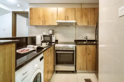 a kitchen with wooden cabinets and a washer and dryer at ShoresInn - Elite 1BR in Dubai Marina in Dubai
