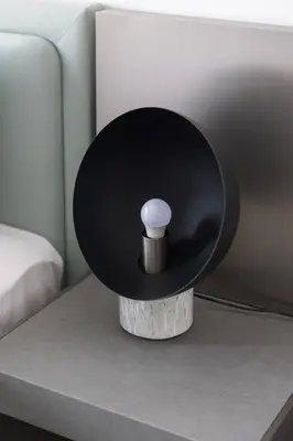 a black and white lamp on a table next to a bed at Brand New Studio 15 mins drive from Business Bay in Dubai