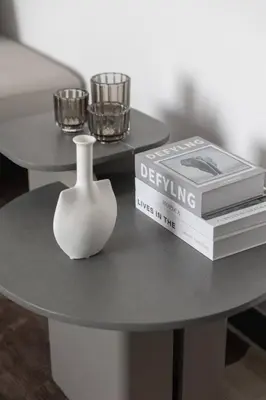 a white vase sitting on a table with a book at Brand New Studio 15 mins drive from Business Bay in Dubai