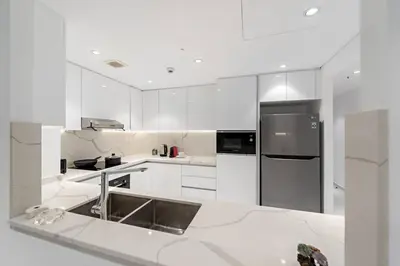 a kitchen with white cabinets and a stainless steel refrigerator at FIRST CLASS 3BR Stylish Sanctuary in Dubai