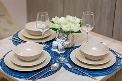 a table with plates and glasses and a vase with flowers at Lovely 1BR in Seven Palm in Dubai