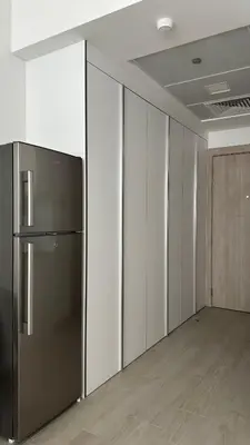 an empty office with a refrigerator in a room at Cozy studio apartment in Jumeirah Village Circle in Dubai