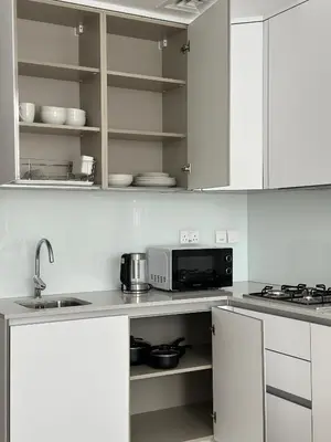 a kitchen with white cabinets and a microwave at Cozy studio apartment in Jumeirah Village Circle in Dubai