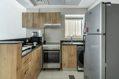 a kitchen with wooden cabinets and a stainless steel refrigerator at ShoresInn - Magnificent 1BR in Dubai Marina in Dubai