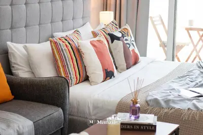 a living room with a couch and pillows on a bed at Manzil - Stylish living in JVC, City Views and Pool in Dubai
