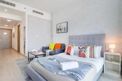a bedroom with a large bed and a couch at Manzil - Stylish living in JVC, City Views and Pool in Dubai
