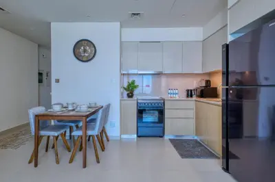 a kitchen with a table and chairs and a clock on the wall at Burj Royale - Luxury Stay with Panoramic Burj Khalifa & Fountain View in Dubai