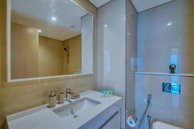 a white bathroom with a sink and a mirror at Burj Royale - Luxury Stay with Panoramic Burj Khalifa & Fountain View in Dubai