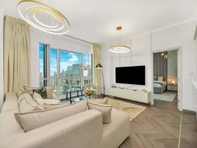 a living room with a white couch and a tv at Luxe 4 bedroom Apartment I Burj Khalifa & Fountain Views I Free Gym, Pool, Parking, Wi-Fi and PS5 I by Skyline Serenity in Dubai