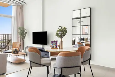 a living room with a table and chairs and a tv at Silkhaus in Collective Tower Luxorious 2BDR in Dubai