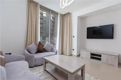 a living room with a couch and a tv at Ahlan HH - Luxury 2BR in Sobha Creek Vistas in Dubai