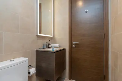 a bathroom with a toilet and a wooden door at Ahlan HH - Luxury 2BR in Sobha Creek Vistas in Dubai