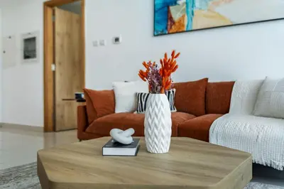 a living room with a couch and a vase on a coffee table at ShoresInn - Waterfront in Heart of Dubai Marina in Dubai