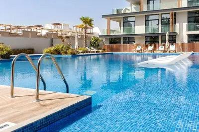 a swimming pool with a white chair in a building at Waves - Elegant Oxford 212 Studio in JVC with City Views in Dubai