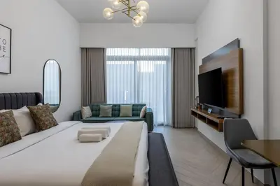 a living room with a large bed and a tv at Waves - Elegant Oxford 212 Studio in JVC with City Views in Dubai